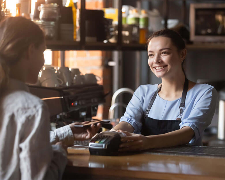 Female customer pay with phone on nfc with smiling barista